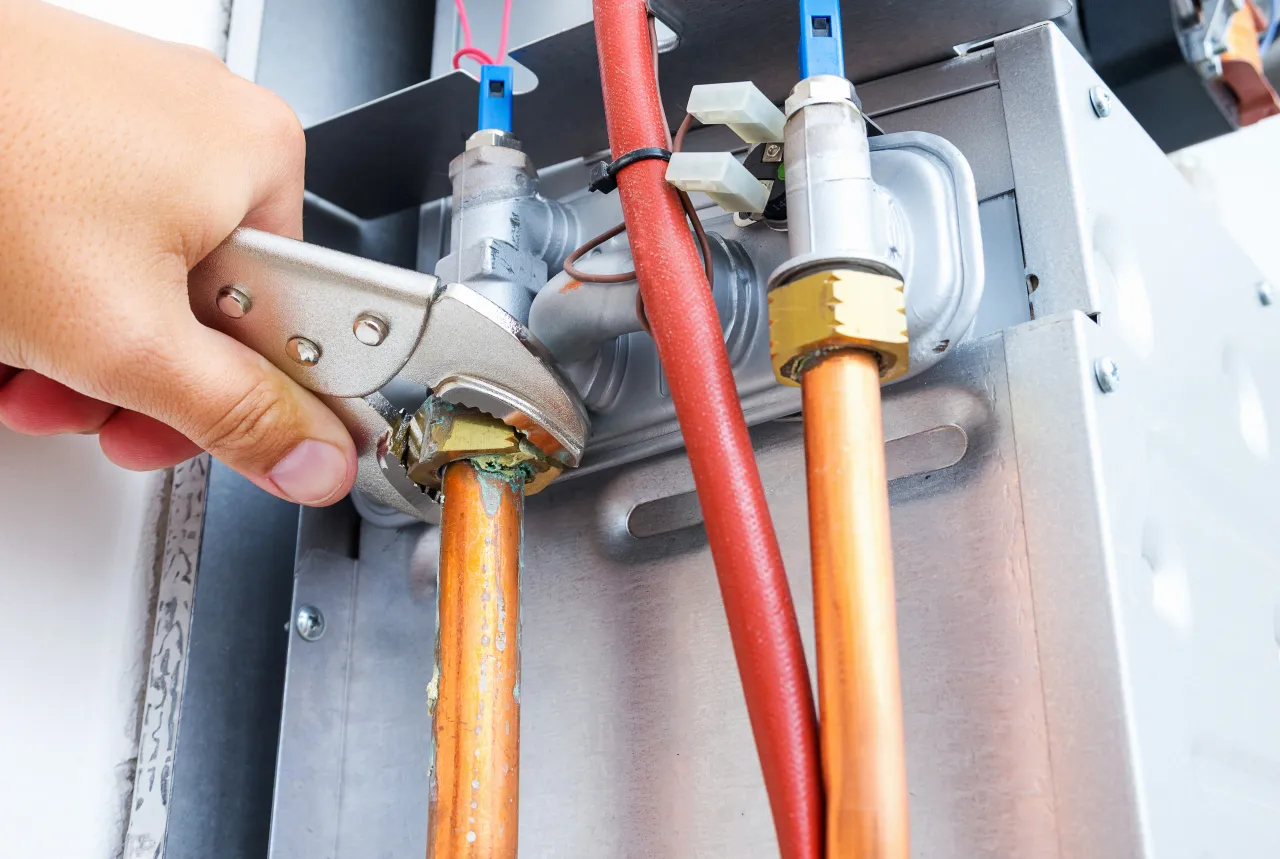 Technician servicing gas and water lines on a tankless water heater