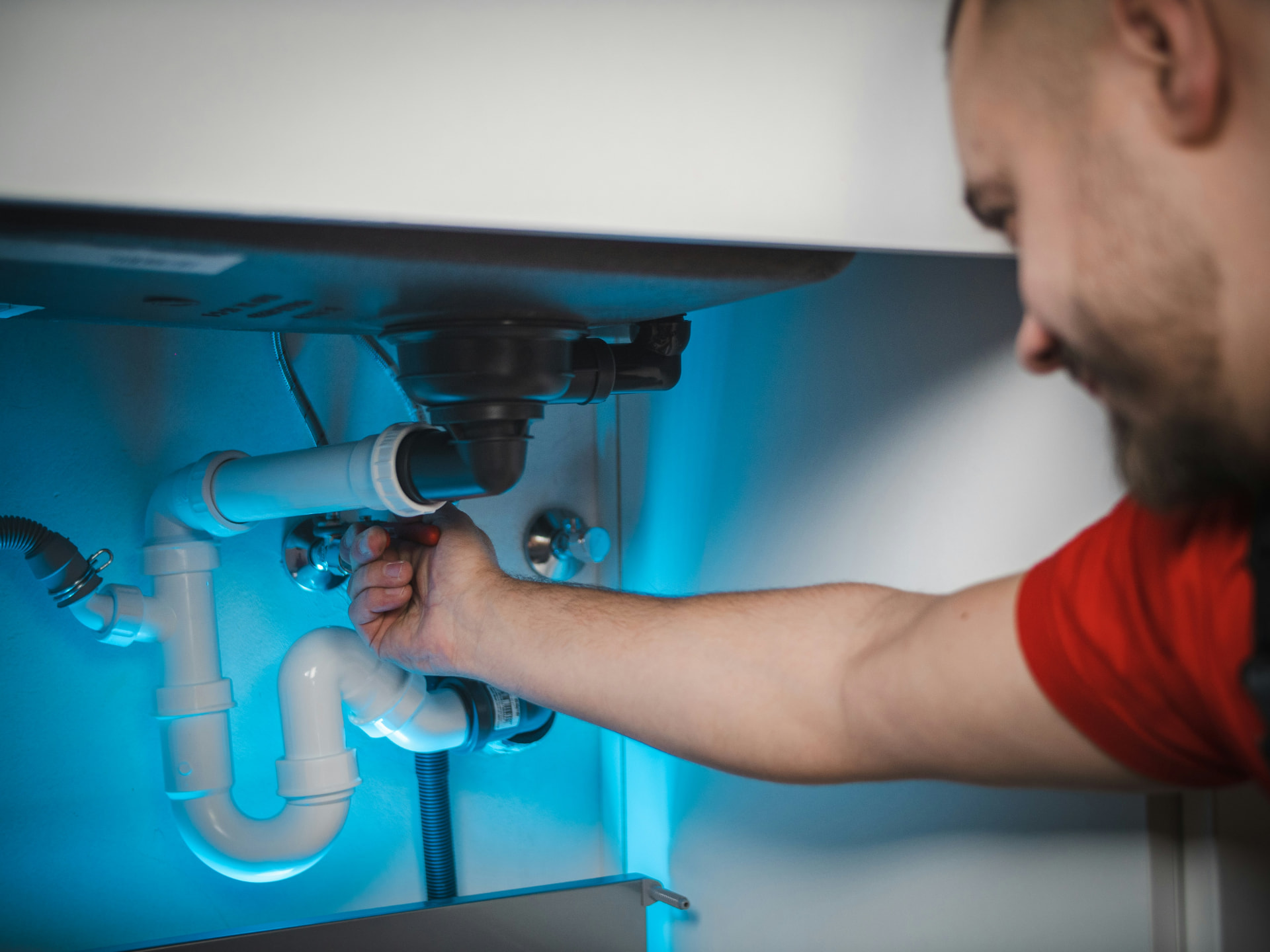 Plumber tightening a fitting under a kitchen sink