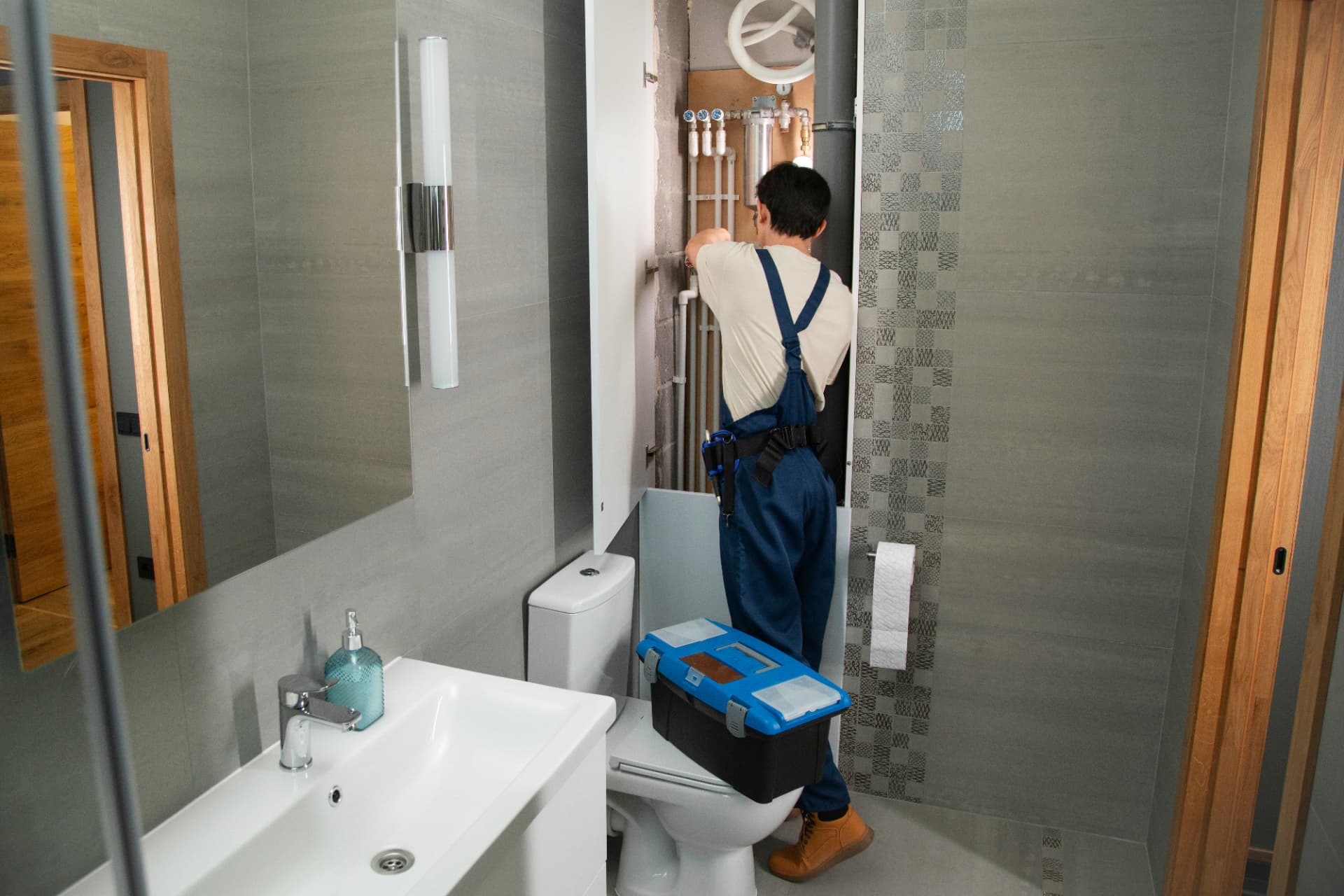 Plumber servicing water lines in a modern bathroom